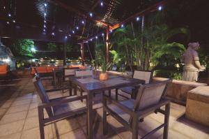 a wooden table and chairs on a patio at night at Hilton Princess San Pedro Sula in San Pedro Sula