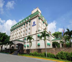 a hotel building with palm trees in front of it at Hilton Princess San Pedro Sula in San Pedro Sula