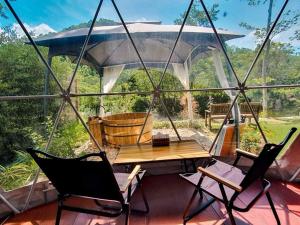 een afgeschermde veranda met een tafel en stoelen bij ไวน์แคมป์ WineCamp โดมติดลำธาร in Ban Cha-om