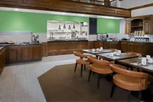 a restaurant with green walls and wooden tables and chairs at Hilton Garden Inn San Antonio Airport in San Antonio