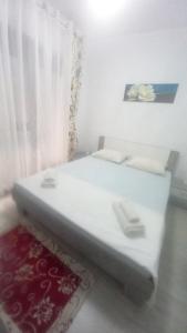 ein weißes Bett mit einem roten Teppich neben einem Fenster in der Unterkunft Casandra in Mamaia Nord – Năvodari