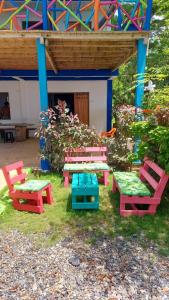 a group of picnic tables and benches in front of a building at Casa hostal playa coral in Capurganá