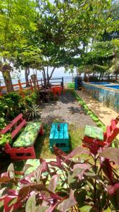 a picnic table and benches next to a swimming pool at Casa hostal playa coral in Capurganá