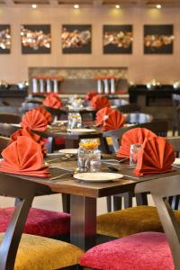uma sala de jantar com mesas e cadeiras com guardanapos vermelhos em HOTEL G EXPRESS Formerly Known as TGB Express em Ahmedabad