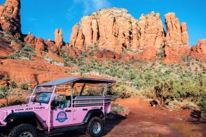 una jeep rosa parcheggiata di fronte a delle rocce rosse di Hilton Sedona Resort at Bell Rock a Sedona