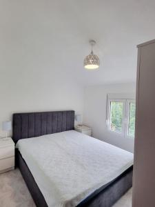 ein weißes Schlafzimmer mit einem großen Bett und einem Fenster in der Unterkunft Cozy House Haj Nehaj in Sutomore