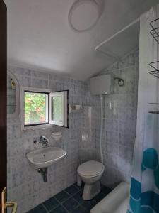 ein Bad mit einem Waschbecken, einem WC und einem Fenster in der Unterkunft Cozy House Haj Nehaj in Sutomore