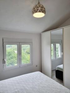 - une chambre blanche avec un lit et 2 fenêtres dans l'établissement Cozy House Haj Nehaj, à Sutomore