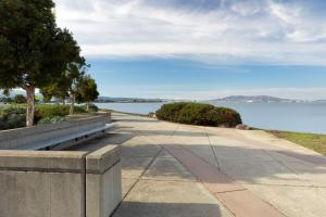 a sidewalk with a bench next to a body of water at DoubleTree by Hilton San Francisco Airport in Burlingame
