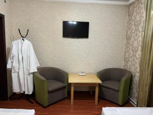 Zimmer mit 2 Stühlen, einem Tisch und einem TV in der Unterkunft Lite Guest House in Bischkek