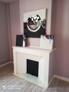 a white fireplace with a picture on the wall at Maison entière au Centre de Villeneuve d'Olmes in Villeneuve dʼOlmes