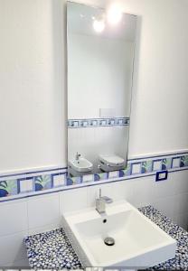 La salle de bains est pourvue d'un lavabo et d'un grand miroir. dans l'établissement DA DANY e ELIA, à Irgoli