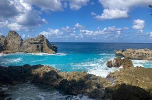 a view of the ocean with rocks in the water at Marina et Piscine 4-5 pers in Saint-François