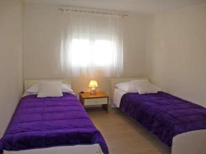 two beds in a room with purple sheets and a window at 4 bedroom apartment with 3 bathrooms and private parking - Apartments Orange in Zadar