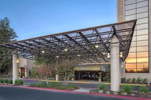 a building with a metal canopy in front of it at Hilton Sacramento Arden West in Sacramento