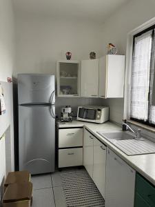 una cocina con nevera de acero inoxidable y armarios blancos en Casa Maria-Appartamento in Villa, en Ispra