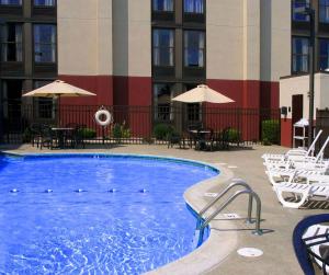 uma piscina num hotel com cadeiras e mesas em Hampton Inn West Springfield em West Springfield