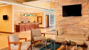 a lobby with chairs and a tv on a brick wall at DoubleTree by Hilton Collinsville/St.Louis in Collinsville