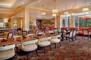 uma sala de jantar com mesas e cadeiras de madeira em Hilton Garden Inn St. Louis Airport em Berkeley