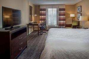 a hotel room with a bed and a flat screen tv at Hilton Garden Inn St. Louis Airport in Berkeley