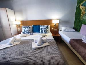two beds in a hotel room with towels on them at Villa Riviera in Stavros +37 photos