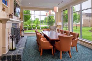 Hilton Garden Inn St. Louis/O'Fallon في أوفالون: غرفة طعام مع طاولة وكراسي ونوافذ