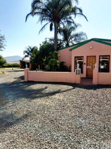 a pink building with a palm tree in front of it at Rietkuil Country Cottages in Cremin