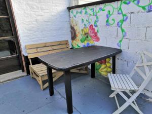 une table de pique-nique et une chaise près d'un mur dans l'établissement Le nid d'hirondelle, à Yzengremer