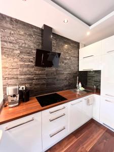 グディニャにあるAltoria Apartamentyの白いキャビネットとレンガの壁が備わるキッチン