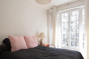a bedroom with a bed and a large window at Calm and bright cocoon in Paris