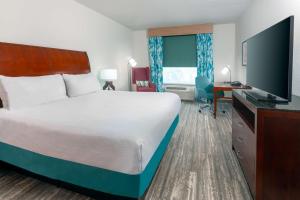 a hotel room with a large bed and a desk at Hilton Garden Inn Tampa Riverview Brandon in Brandon