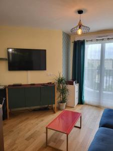 uma sala de estar com um sofá azul e uma televisão de ecrã plano em Bel appartement à Rueil-Malmaison em Rueil-Malmaison