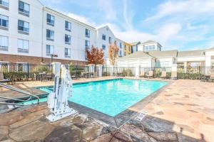 a swimming pool with chairs and a building at Hilton Garden Inn Tulsa South in Tulsa