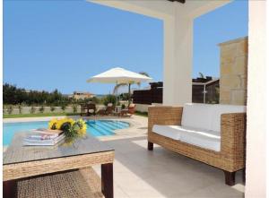 eine Terrasse mit einem Sofa, einem Tisch und einem Sonnenschirm in der Unterkunft Paradise Latchi Villa in Polis Chrysochous