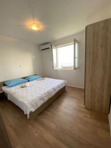 ein Schlafzimmer mit einem großen Bett mit blauen Kissen und einem Fenster in der Unterkunft Apartment Leonardo in Makarska