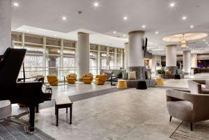 a lobby with a grand piano and yellow chairs at DoubleTree by Hilton Tulsa at Warren Place in Tulsa
