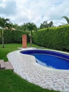 ein Pool in einem Garten neben einer Hecke in der Unterkunft Habitación tranquila en casa campestre in Pereira