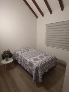 a bedroom with a bed and a table and a window at Habitación tranquila en casa campestre in Pereira