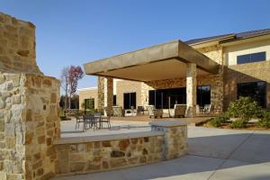 - un bâtiment en pierre avec une terrasse dotée de tables et de chaises dans l'établissement Hilton Garden Inn Texarkana, à Texarkana - Texas