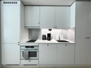 a white kitchen with white cabinets and a sink at Transit Apartment HEL Airport in Vantaa