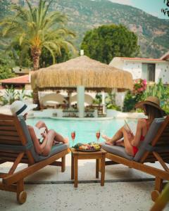 two women laying in lounge chairs next to a swimming pool at Kassandra Boutique Hotel in Oludeniz