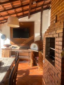 uma sala de estar com uma lareira de tijolos e uma televisão em Loft da Beth na serra em Petrópolis