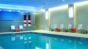 a swimming pool with red chairs and tables in a building at Embassy Suites by Hilton Alexandria Old Town in Alexandria