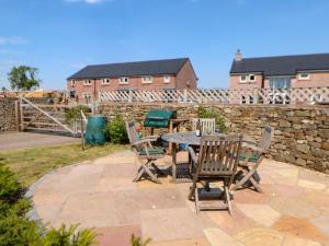 a patio with a table and chairs and a stone wall at Larch House in Penrith