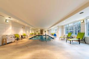 a pool in a room with green chairs and tables at Hilton Garden Inn Winchester in Winchester