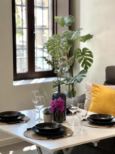 a table with plates and glasses and a vase with flowers at Lofts Jumaral - La Magdalena in Córdoba