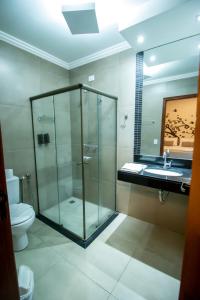 La salle de bains est pourvue d'une douche en verre et de toilettes. dans l'établissement Pousada Vitalis, à Olímpia