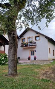 une maison blanche avec un arbre en face dans l'établissement Room "Iva", à Josipdol