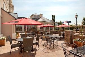 a patio with tables and chairs with red umbrellas at Hilton Garden Inn West Edmonton in Edmonton