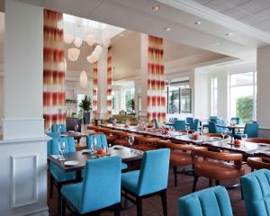 a dining room with tables and blue chairs at Hilton Garden Inn Montreal Airport in Dorval